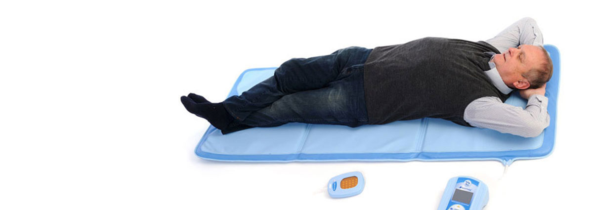 Mann bei einer Magnetfeldbehandlung liegend auf einer Applikatormatte